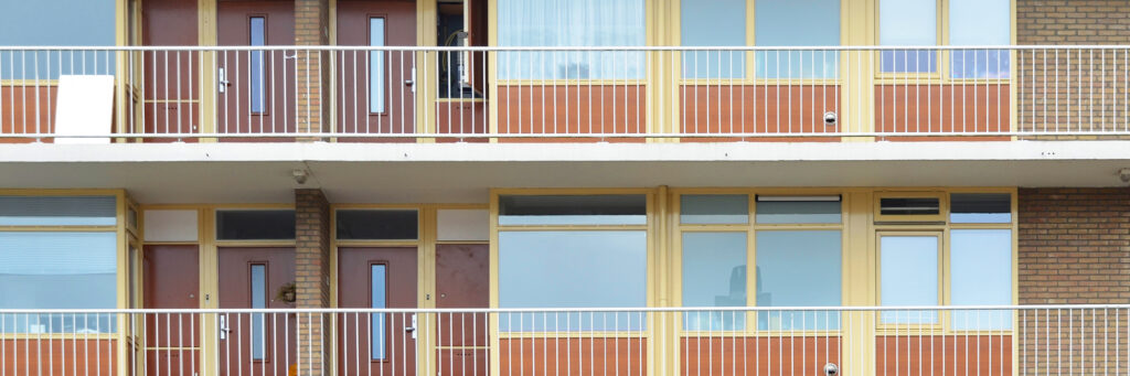 Appartementencomplex met gele kozijnen met rode platen, rode deuren en gele balustrade