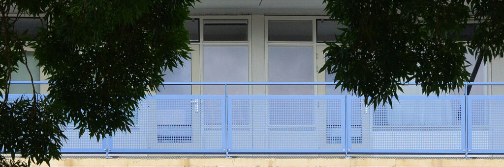 Appartementencomplex met gele kozijnen, blauwe balustrade en bomen