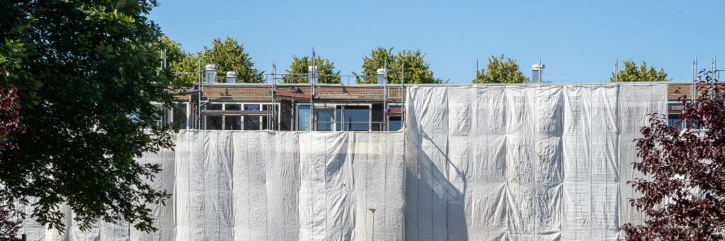 Appartementen met steigers ervoor en witte doeken met bomen ervoor