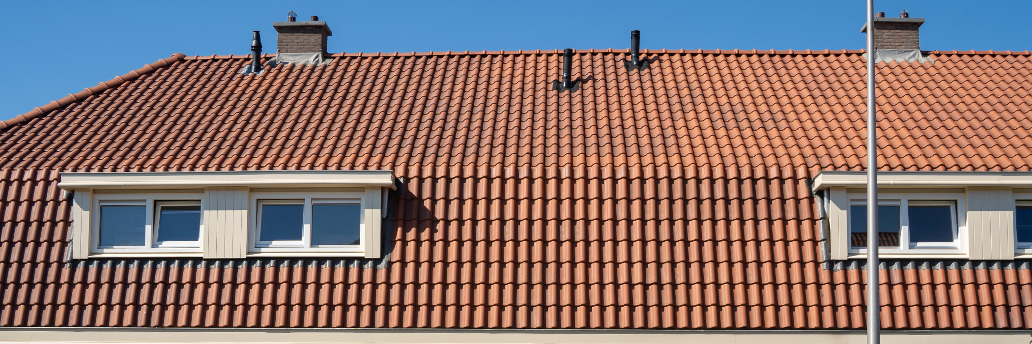 Woningen bovenste verdieping, rode dakpannen, crème dakkapellen en witte ramen