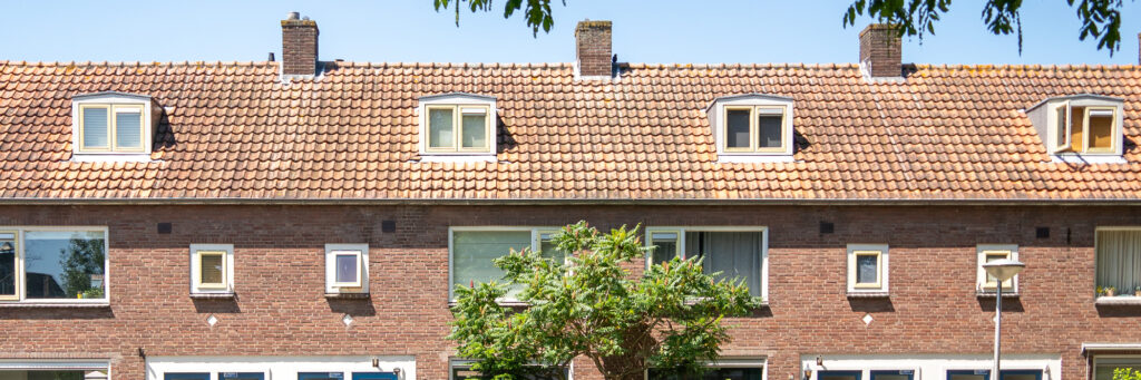 Woningen bovenste verdieping met bruine bakstenen gevel, witte kozijnen, gele ramen en een boom voor de deur