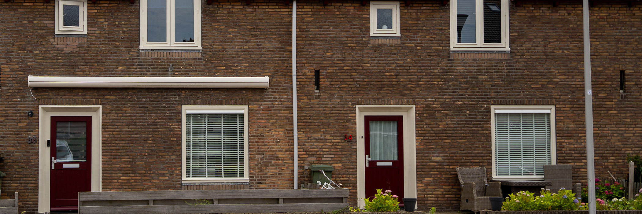 Woningen met bruine bakstenen gevel, crème kozijnen en rode deuren