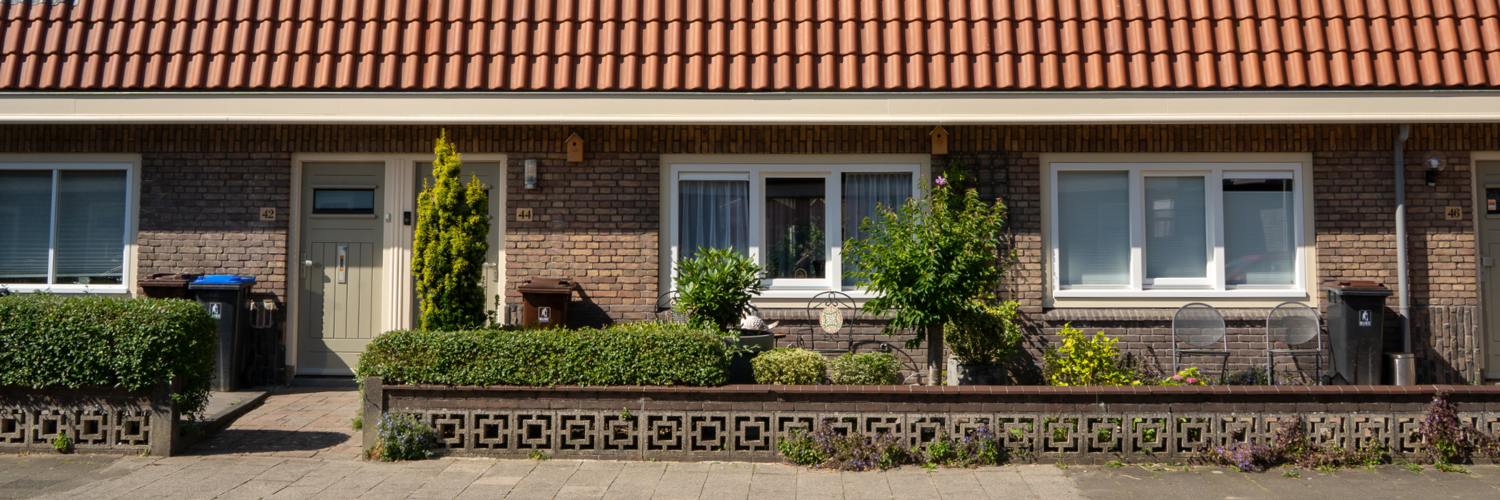 Woningen met bruine bakstenen gevels, crème kozijnen en deuren met witte ramen