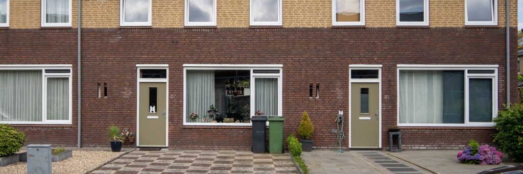 Woningen met twee kleuren bruin bakstenen gevel, witte kozijnen en bruingroene deuren