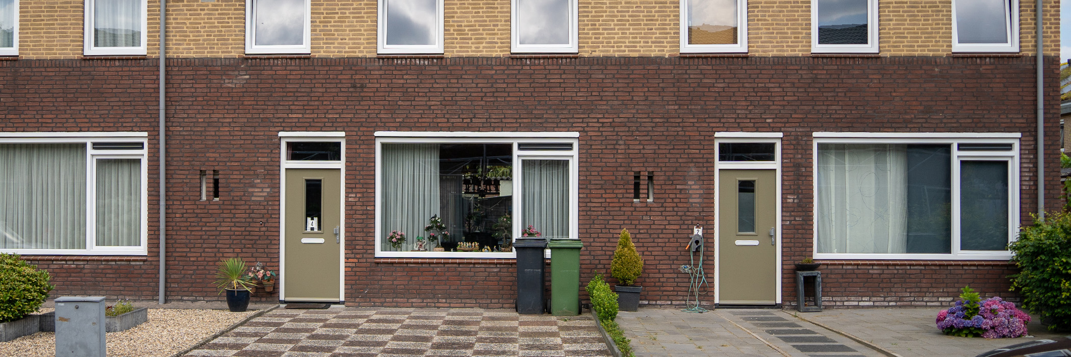 Woningen met twee kleuren bruin bakstenen gevel, witte kozijnen en bruingroene deuren