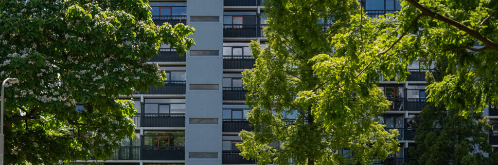 Appartementencomplex met blauwe gevel, blauwe balustrade en bomen ervoor