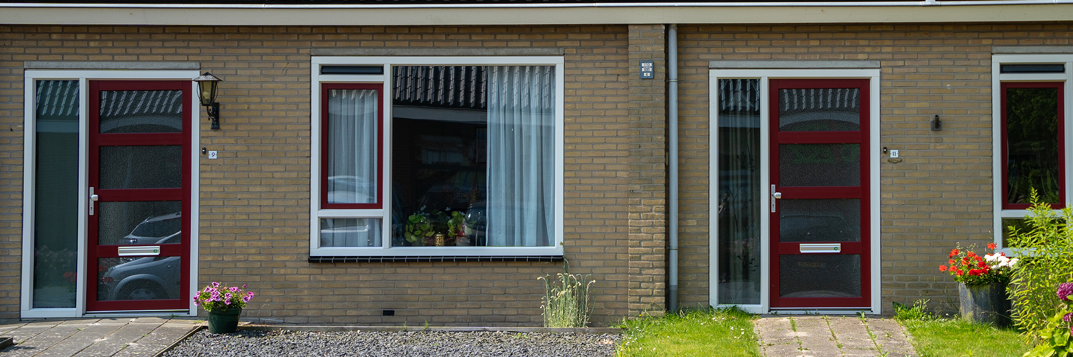 Woningen met bruine bakstenen gevel witte kozijnen met rode deuren en ramen