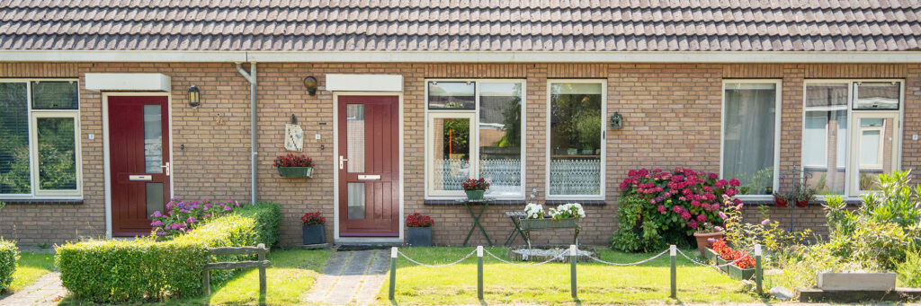 Woningen met bruine bakstenen gevel, donkere dakpannen, witte kozijnen en rode deuren