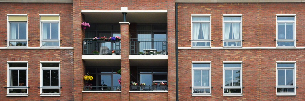 Appartementencomplex met rode bakstenen gevel, witte kozijnen en zwarte balkon balustrade