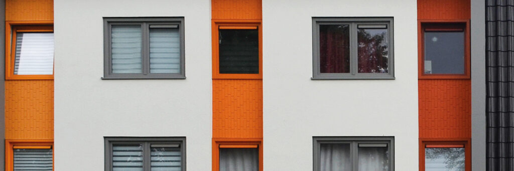 Appartementencomplex met witte gevel met oranje vlakken en grijze kozijnen