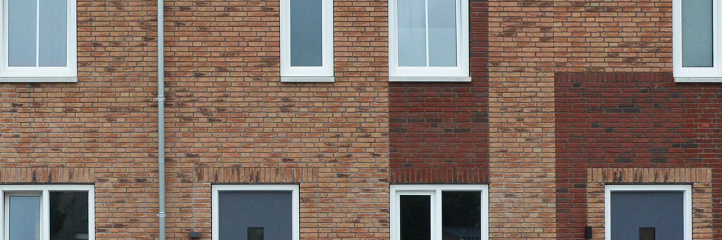 Woningen met bruine bakstenen gevel, witte kozijnen en blauwe deuren