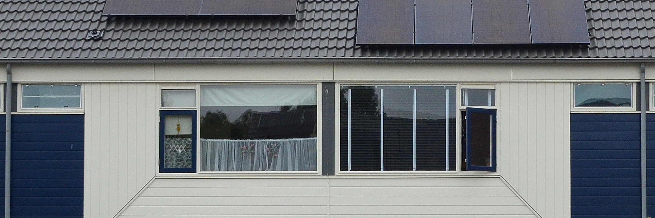 Woningen met witte gevel, witte kozijnen, zwarte daken met zonnepanelen
