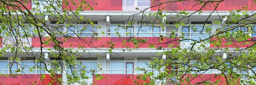 Appartementencomplex met rode deuren en rode balustrade met bomen