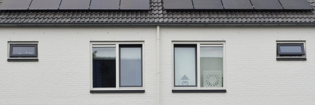 Woningen met witte gevel, witte kozijnen, zwarte daken met zonnepanelen