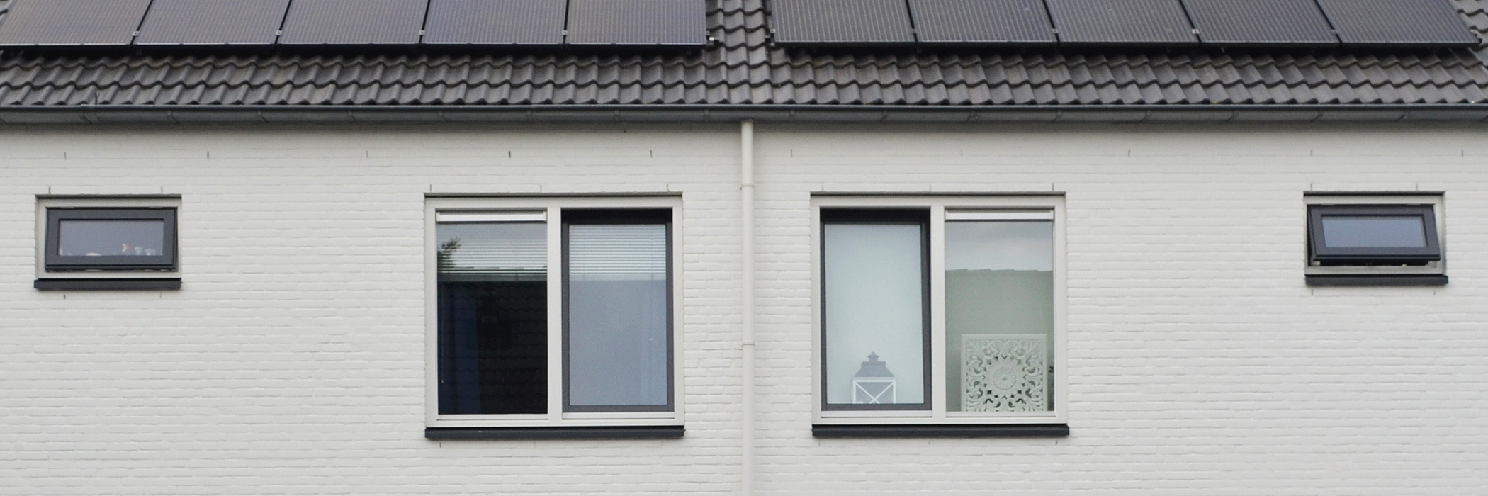 Woningen met witte gevel, witte kozijnen, zwarte daken met zonnepanelen