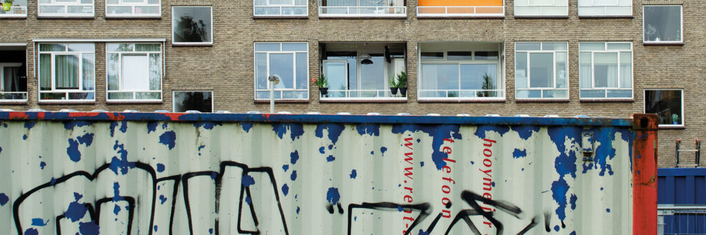 Appartementencomplex met bruine bakstenen gevel met een container ervoor