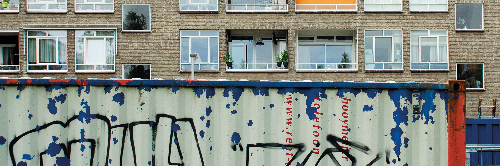 Appartementencomplex met bruine bakstenen gevel met een container ervoor