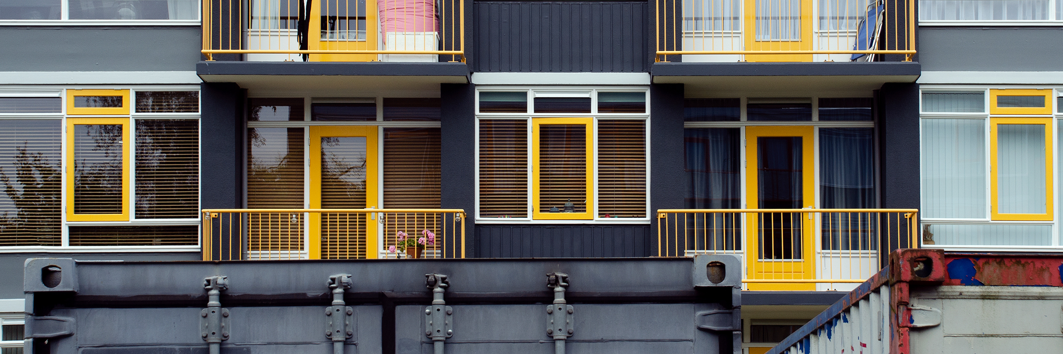 Appartementencomplex met zwarte gevel, witte kozijnen en gele deuren