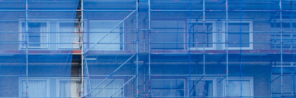 Woningen die worden verbouwd met stijgers voor de deur met blauwe doeken