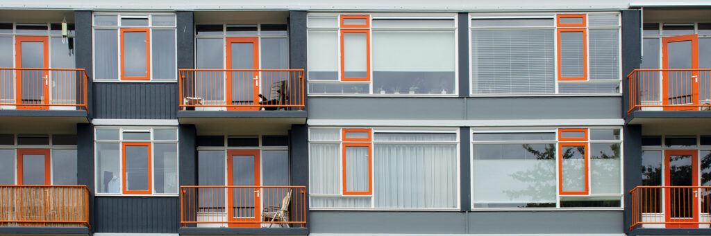 Appartementen met zwarte bakstenen gevel met witte kozijnen, oranje deuren en balustrade