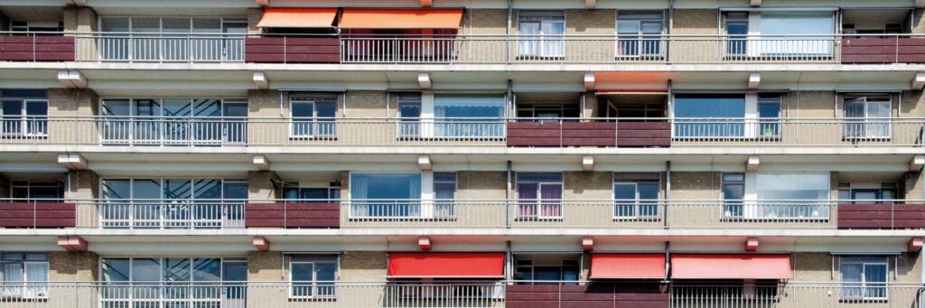 Appartementencomplex met crème gevel, witte kozijnen en rode zonwering