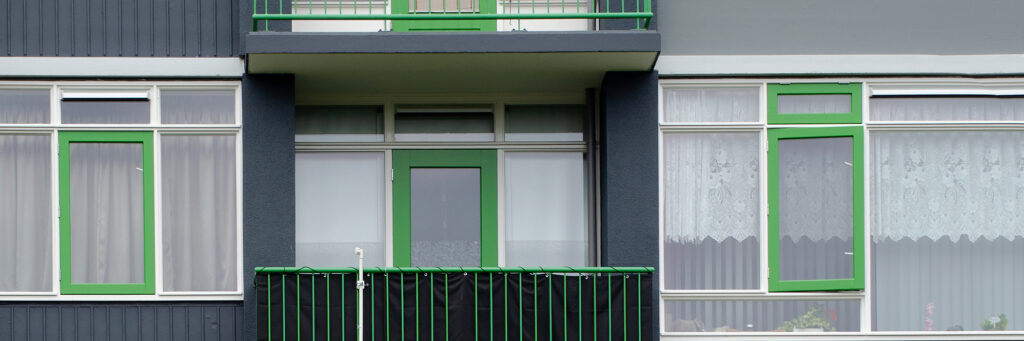 Appartementencomplex met zwarte gevel, witte kozijnen met groene balustrade