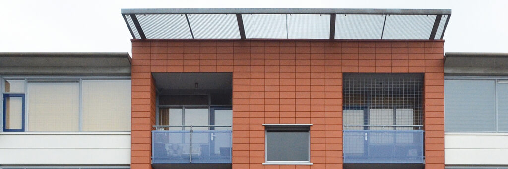Appartementencomplex met donkerrode gevel met witte kozijnen en blauwe balustrade