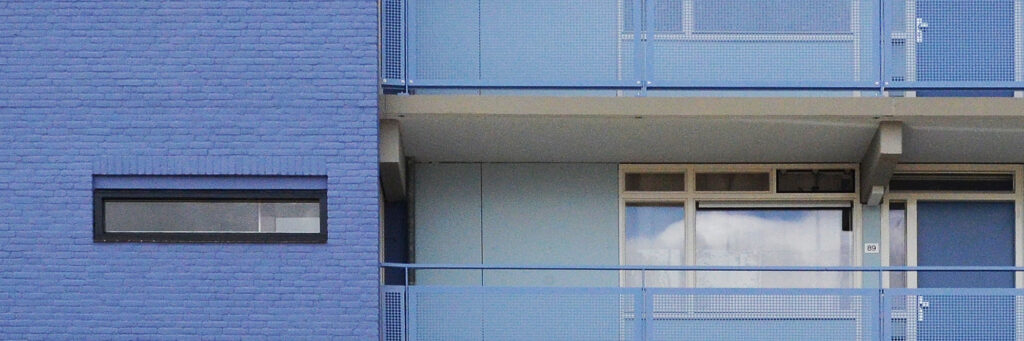 Appartementencomplex met blauwe bakstenen gevel, met witte kozijnen en blauwe balustrade