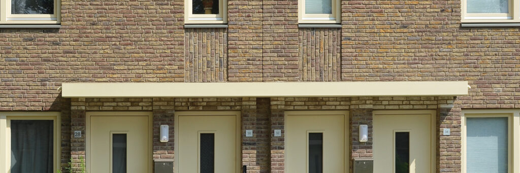Woningen met bruine bakstenen gevel en gele deuren en kozijnen