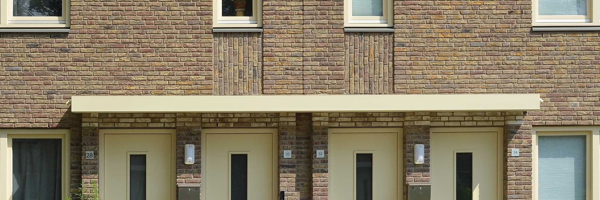 Woningen met bruine bakstenen gevel en gele deuren en kozijnen