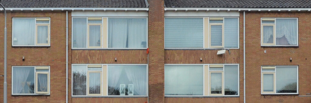 Appartementencomplex met bruine bakstenen gevel, witte kozijnen met gele ramen