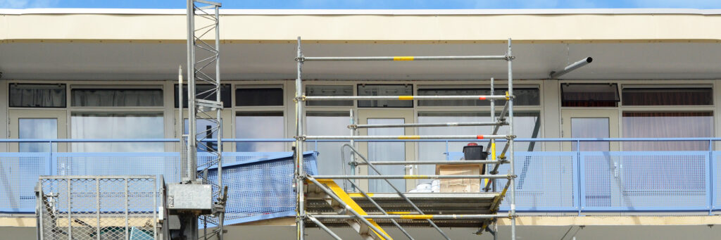 Appartementencomplex met witte kozijnen, crème deuren, blauwe balustrade en een steiger voor de deur