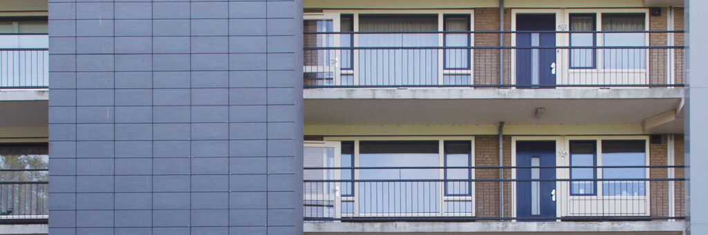 Appartementencomplex met bruine bakstenen muur, witte kozijnen, blauwe ramen, deuren en balustrade