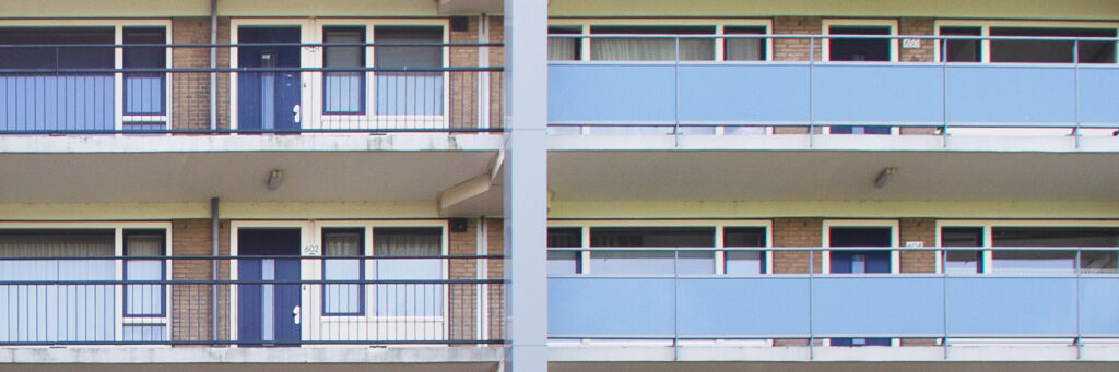 Appartementencomplex met bruine bakstenen gevel, witte kozijnen, blauwe deuren, ramen en balustrade