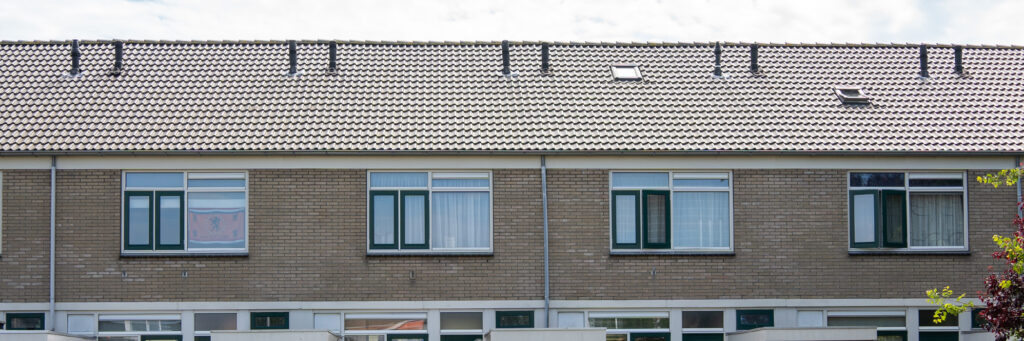 Woningen met bruine bakstenen gevel, witte kozijnen en groene ramen