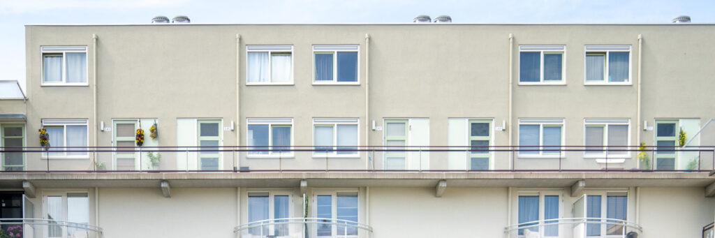 Woningen met crème gevel, witte kozijnen en lichtgroene ramen en deuren