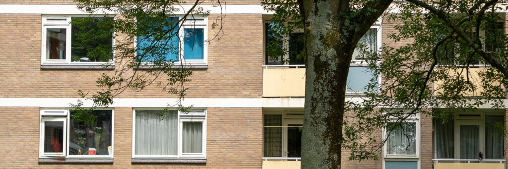 Appartementencomplex met bruine bakstenen gevel, witte kozijnen en gele balkons