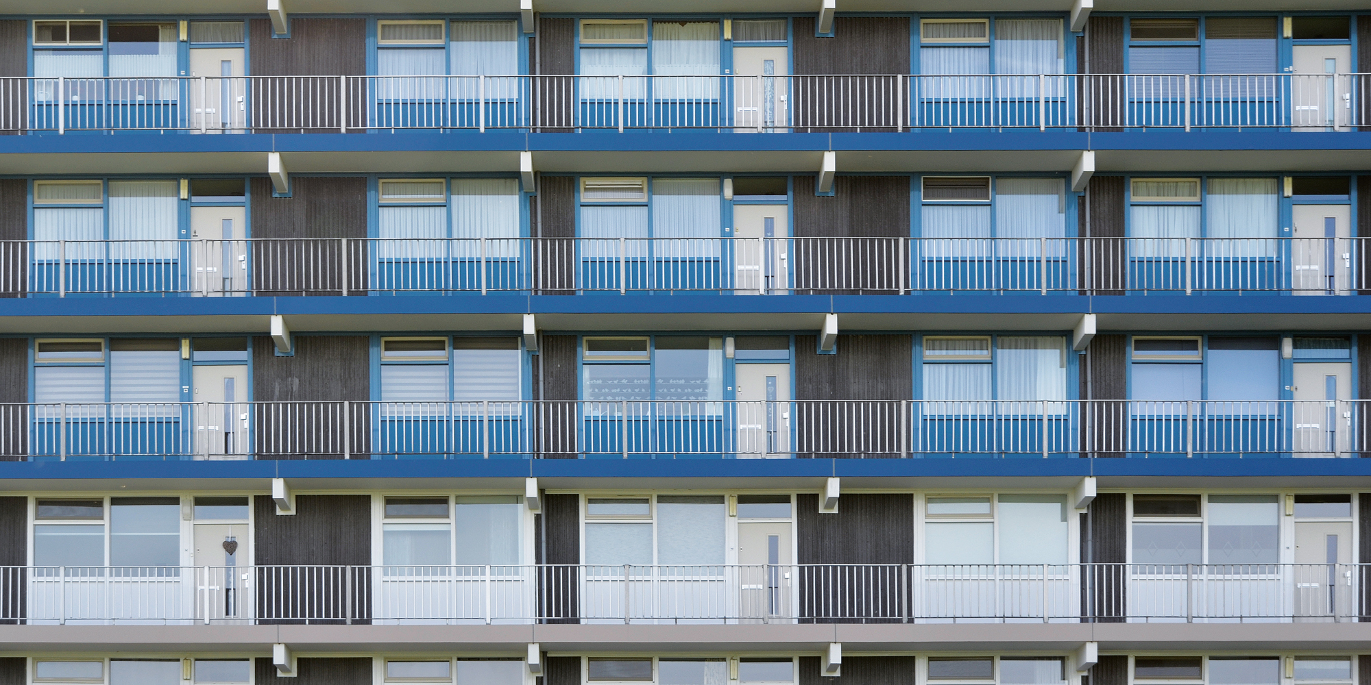 Appartementencomplex met grijze gevel, witte kozijnen en blauwe balustrade