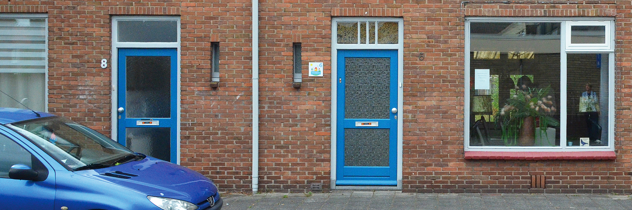 Woningen met blauwe voordeuren gebouwd van bakstenen.