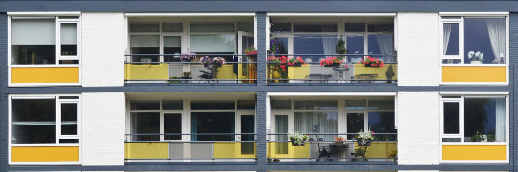 Appartementen met witte bakstenen gevel, witte kozijnen met gele platen eronder, grijze balkon balustrades
