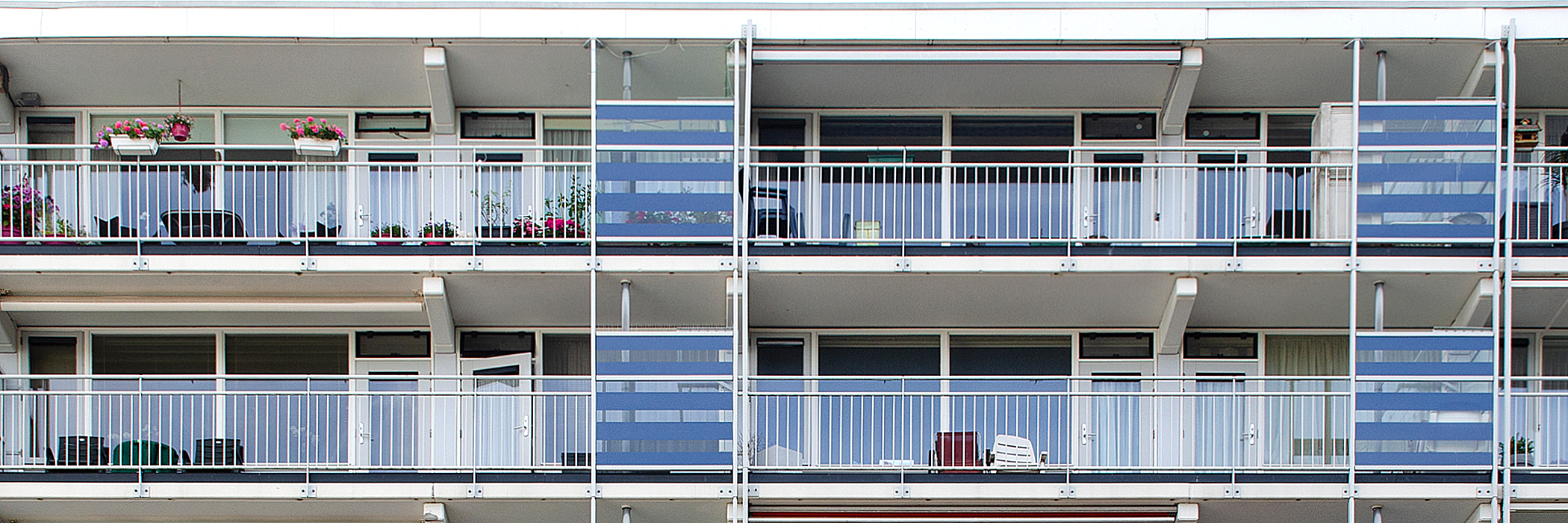 Appartementen bestaande uit veel glas met witte kozijnen en deuren. Appartementen bevatten een wit balkon met een wit hekje.