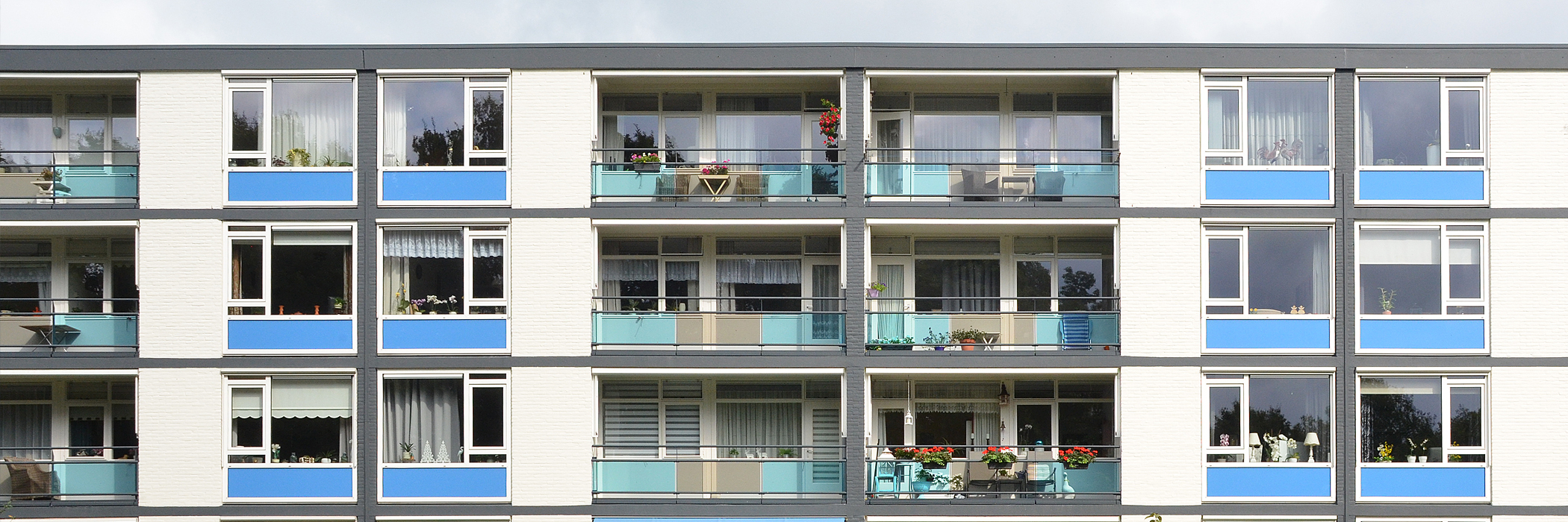 Appartementen met witte bakstenen gevel, witte kozijnen met blauwe platen eronder, grijze balkon balustrades