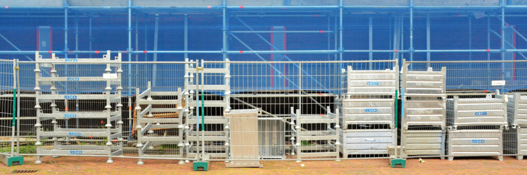 Appartementen in de bouw, met bouwmaterialen die achter een hek staan