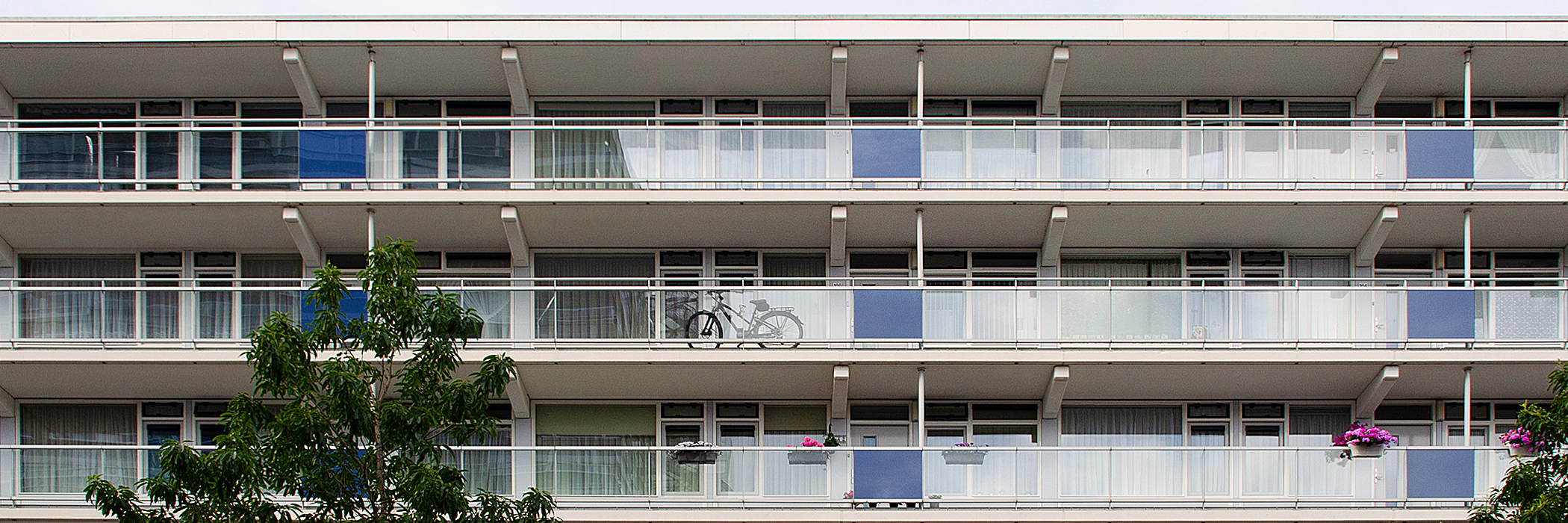 Appartementen met witte kozijnen, witte balustrade en blauwe vlakken voor de balustrades