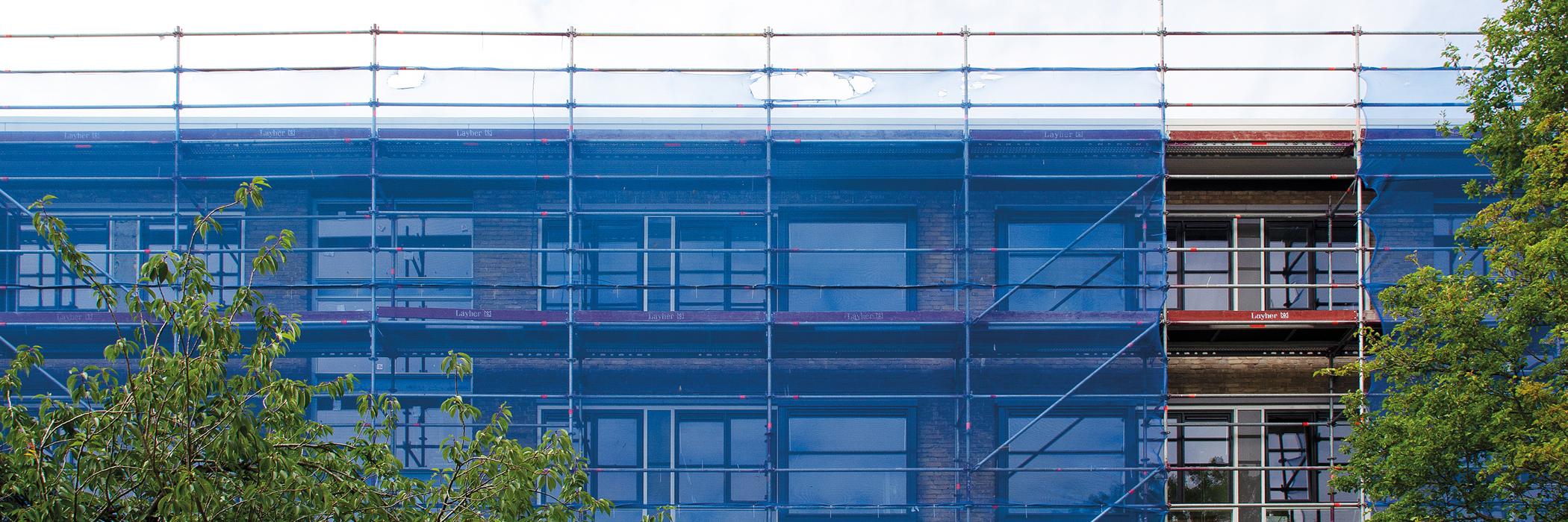 Appartementen met bruine bakstenen geval met een steiger voor de deur met blauwe netten en twee bomen