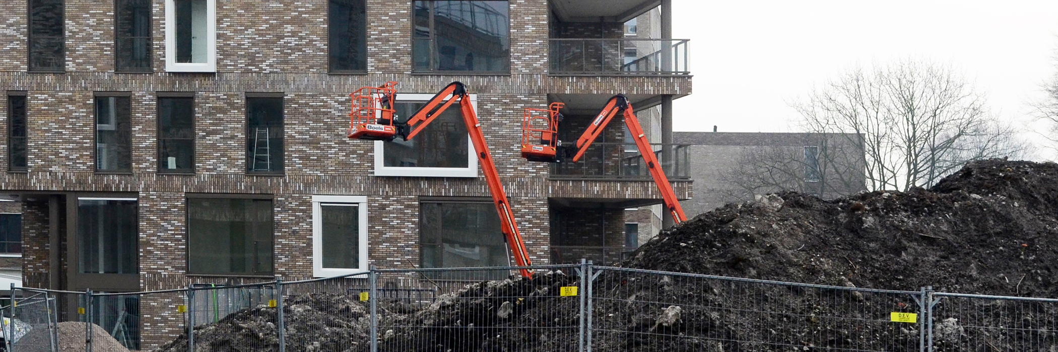 Appartementen van verschillende kleuren bakstenen met witte en donkere kozijnen, de hoek woning heeft een balkon