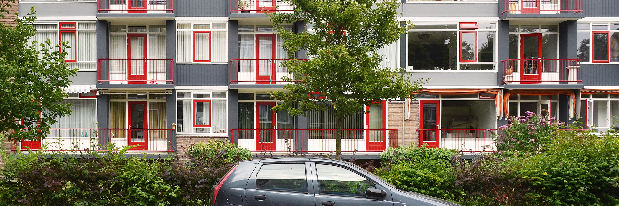 Appartementen met rode deuren, wit en rode kozijnen.