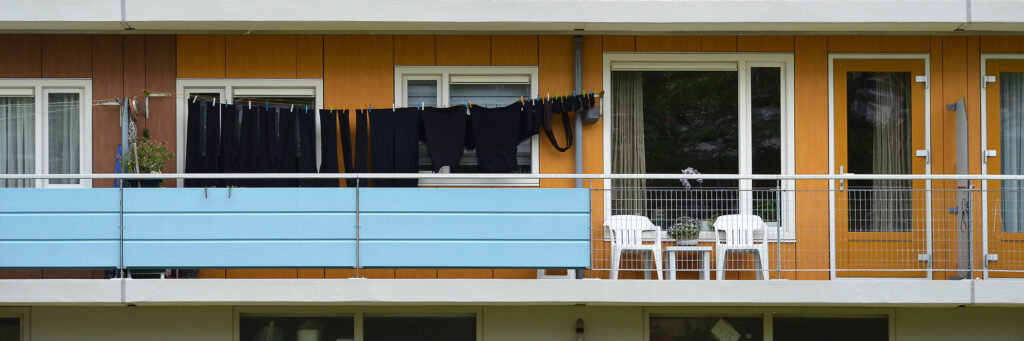 Appartementen met oranje deur, oranje gevel en witte kozijnen met een balkon.