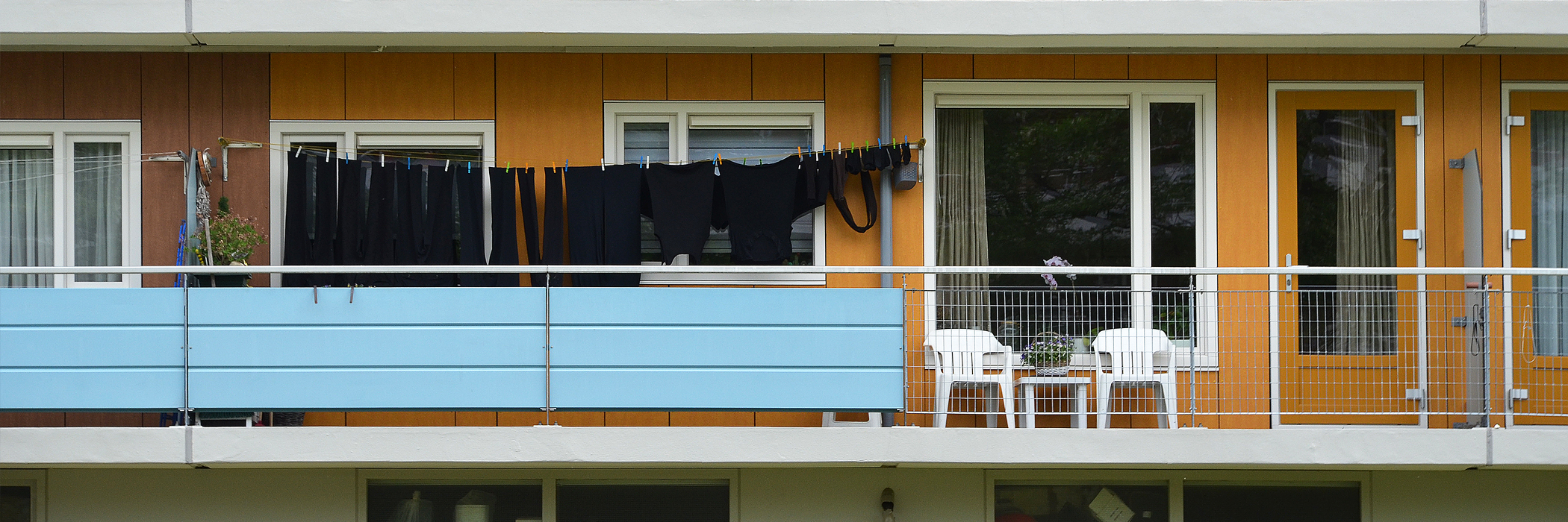 Appartementen met oranje deur, oranje gevel en witte kozijnen met een balkon.