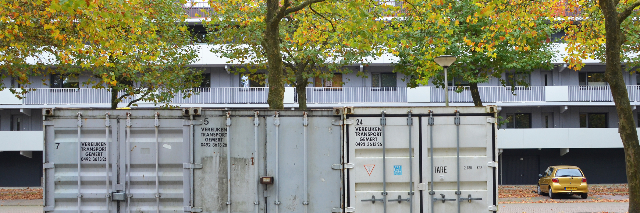 Appartementen met een grijze gevel, grijze kozijnen en grijze deuren met een balkon.